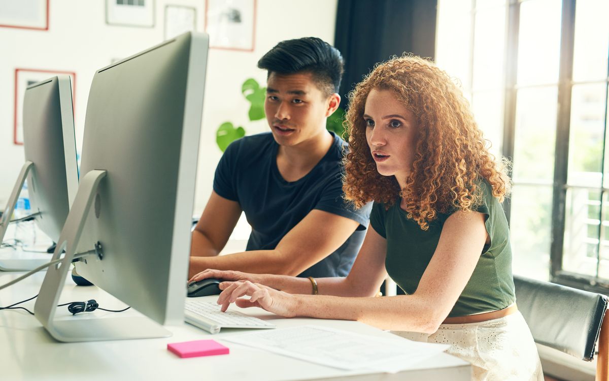 Student pair programming with one pointing at the screen and the other typing