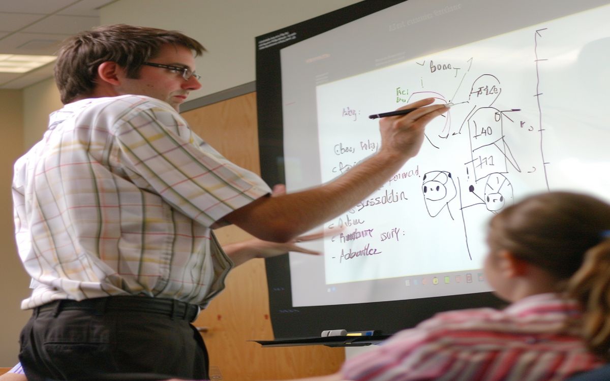 Teacher demonstrating a coding concept on a whiteboard